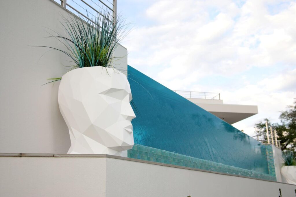 Contemporary infinity-edge pool with sculptural planters overlooking the lake at Canvas Sur in Windermere, Florida.